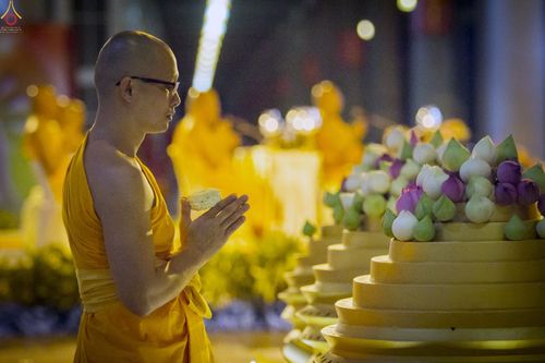 พระภิกษุสงฆ์พนมมือถือดอกบัวพับกลีบในพิธีกรรมทางศาสนา
