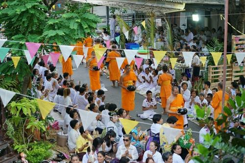 พระสงฆ์เดินรับบิณฑบาตจากพุทธศาสนิกชนที่นั่งรอตักบาตรสองฝั่งถนนในงานพิธีตักบาตรย้อนวันวาน