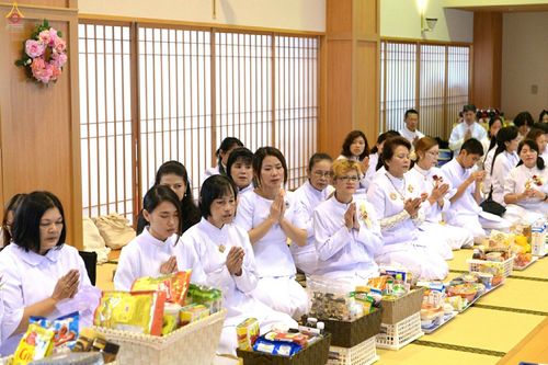 พุทธศาสนิกชนสวมชุดขาวนั่งพนมมือร่วมพิธีทอดกฐินภายในวัดพระธรรมกายคานากาว่า