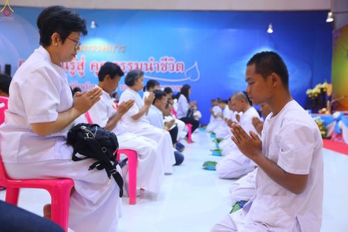 ผู้เข้าร่วมพิธีตัดปอยผมธรรมทายาทสวมชุดขาวนั่งพนมมือในโครงการอุปสมบทหมู่ ณ ห้างทวีกิจคอมเพล็กซ์ จังหวัดสระบุรี