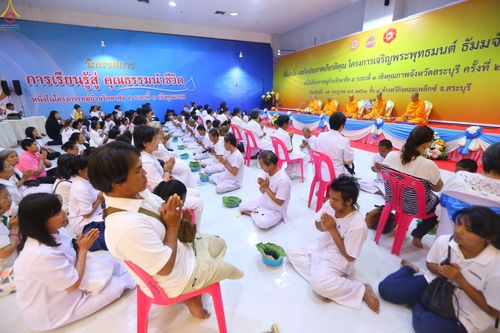 พุทธศาสนิกชนในชุดขาวนั่งพนมมือร่วมพิธีตัดปอยผมธรรมทายาทภายในห้างทวีกิจคอมเพล็กซ์ จังหวัดสระบุรี