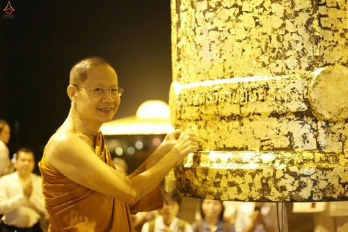 พระภิกษุกำลังปิดทองระฆังธรรมขนาดใหญ่ในพิธีทางศาสนา