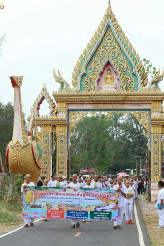 กลุ่มสามเณรเดินขบวนถือป้ายโครงการบรรพชาสามเณรฟื้นฟูพระพุทธศาสนาหน้าซุ้มประตูวัดวัฒนาราม