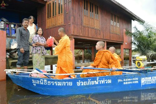 พระภิกษุสงฆ์มอบถุงยังชีพให้ชาวบ้านบนเรือท้องแบนในพื้นที่น้ำท่วม