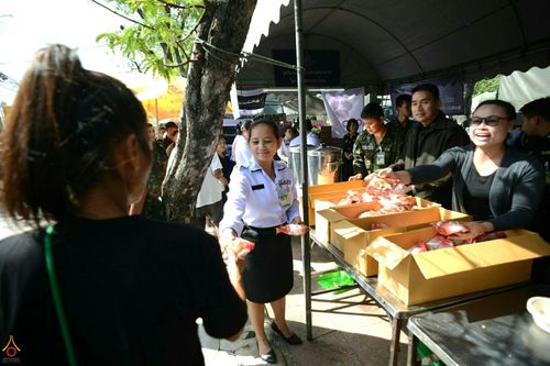 เจ้าหน้าที่และจิตอาสากำลังแจกจ่ายอาหารและน้ำดื่มให้แก่ประชาชนที่มาสักการะพระบรมศพฯ