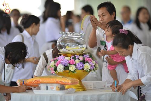 พุทธศาสนิกชนกำลังเขียนชื่อญาติผู้ล่วงลับเพื่อทำพิธีอุทิศส่วนกุศลในงานบุพเปตพลีที่วัดพระธรรมกาย