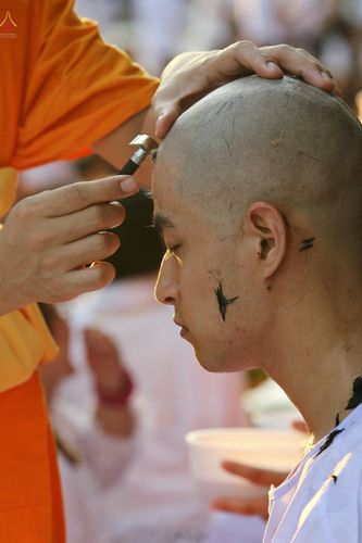 พระภิกษุสงฆ์กำลังปลงผมให้นาคในพิธีบรรพชาอุปสมบทหมู่