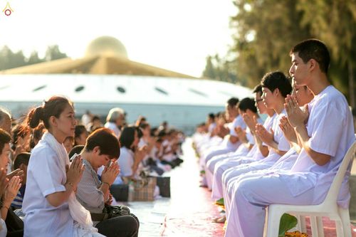 นาคธรรมทายาทและญาติโยมนั่งพนมมือในพิธีบรรพชาอุปสมบทหมู่