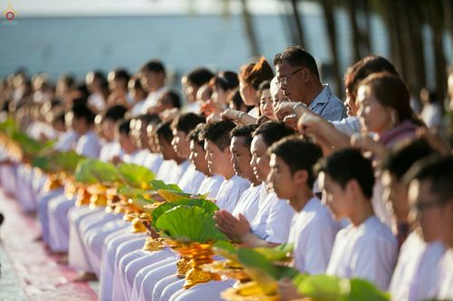 กลุ่มนาคธรรมทายาทในชุดขาวนั่งพนมมือถือพานดอกบัวในพิธีบรรพชาอุปสมบท
