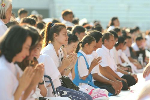 กลุ่มพุทธศาสนิกชนแต่งกายด้วยชุดสีขาวนั่งพนมมือด้วยความสงบในพิธีบรรพชาอุปสมบทหมู่นาคธรรมทายาท