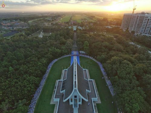 กลุ่มนาคในชุดขาวเข้าแถวรอบอาคารทรงไทยในพิธีบรรพชาอุปสมบทหมู่นาคธรรมทายาท