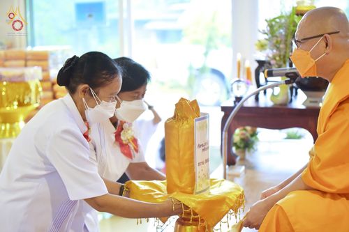 พุทธศาสนิกชนสวมชุดขาวถวายเครื่องกฐินแด่พระภิกษุสงฆ์ในพิธีทอดกฐินสามัคคี