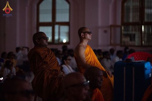 พระสงฆ์สวมจีวรสีส้มและสีน้ำตาลนั่งร่วมกิจกรรมในอาคารช่วงโครงการบรรพชาสามเณรที่ประเทศอินเดีย