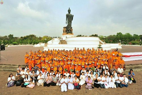 กลุ่มสามเณรและพุทธศาสนิกชนจำนวนมากนั่งและยืนถ่ายภาพร่วมกันหน้าองค์พระประธานพุทธมณฑล