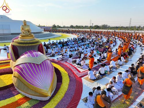พระภิกษุสงฆ์และพุทธศาสนิกชนชุดขาวร่วมพิธีต้อนรับพระธรรมยาตรา บริเวณลานอนุสรณ์สถานบางปลาที่มีการประดับตกแต่งด้วยดอกไม้อย่างสวยงาม