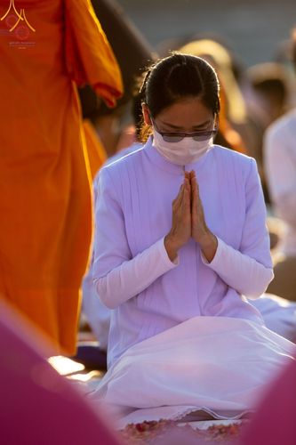 หญิงสวมชุดขาวพนมมือในพิธีต้อนรับพระธรรมยาตรา
