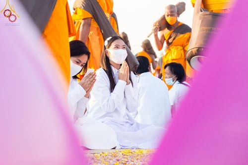 พุทธศาสนิกชนชุดขาวนั่งพนมมือต้อนรับคณะพระธรรมยาตราที่วัดบางปลา