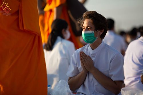 ชายหนุ่มสวมชุดขาวพนมมือด้วยความศรัทธาในพิธีต้อนรับพระธรรมยาตรา