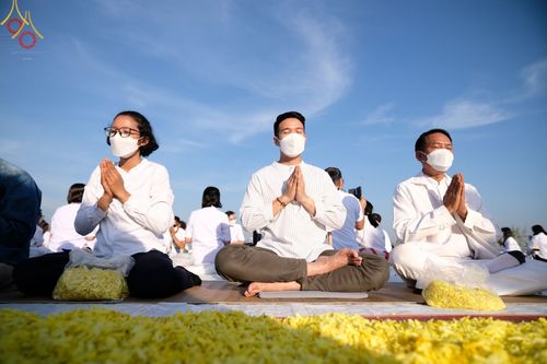 กลุ่มพุทธศาสนิกชนสวมชุดขาวนั่งสมาธิพนมมือในโครงการธรรมยาตรากตัญญูบูชา