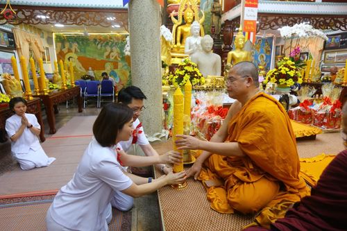 พุทธศาสนิกชนกำลังถวายเทียนพรรษาแด่พระภิกษุสงฆ์ในพิธีทางศาสนา