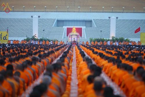 พระภิกษุสงฆ์จำนวนมากนั่งเรียงแถวประกอบพิธีกรรมทางศาสนาหน้าแท่นประดิษฐานรูปหล่อทองคำ