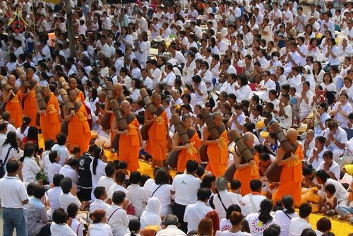 พระภิกษุสงฆ์เดินธุดงค์ท่ามกลางพุทธศาสนิกชนที่สวมชุดขาวโปรยกลีบดอกไม้ต้อนรับ