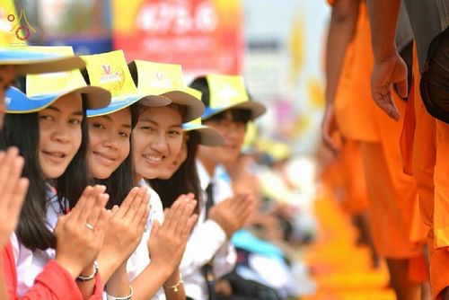 กลุ่มนักเรียนหญิงสวมหมวกสีเหลืองพนมมือต้อนรับพระธุดงค์ในโครงการธุดงค์ธรรมชัย
