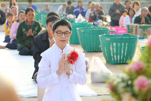 หญิงไทยสวมชุดขาวพนมมือไหว้ในพิธีตักบาตรข้าวสารอาหารแห้งที่วัดกิ่วลม