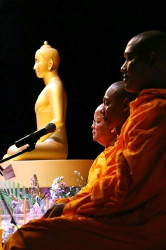 พระสงฆ์นั่งสมาธิในพิธีวิสาขบูชาโดยมีพระพุทธรูปสีทองเป็นฉากหลัง