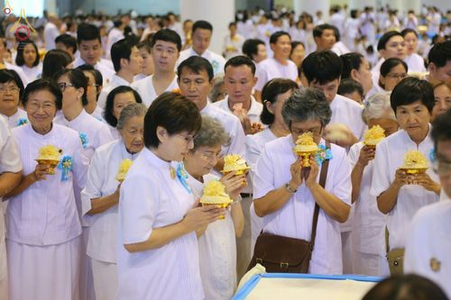 พุทธศาสนิกชนชุดขาวถือพานดอกไม้ประกอบพิธีบูชาข้าวพระในวันครูผู้ค้นพบวิชชาธรรมกาย