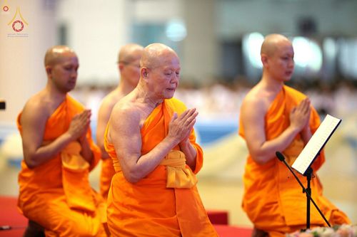 พระภิกษุสงฆ์หลายรูปกำลังนั่งพนมมือสวดมนต์ในพิธีกรรมทางศาสนา