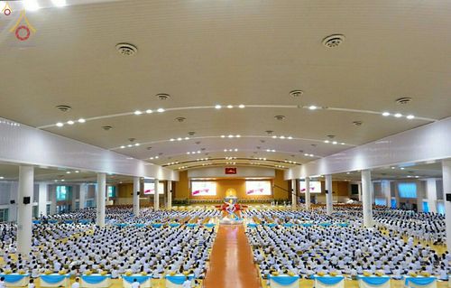 พุทธศาสนิกชนจำนวนมากสวมชุดขาวนั่งปฏิบัติธรรมภายในหอประชุมขนาดใหญ่ในวันครูผู้ค้นพบวิชชาธรรมกาย