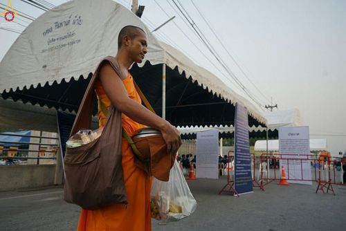 พระภิกษุเดินรับบิณฑบาตพร้อมย่ามและบาตรภายในบริเวณวัดพระธรรมกาย